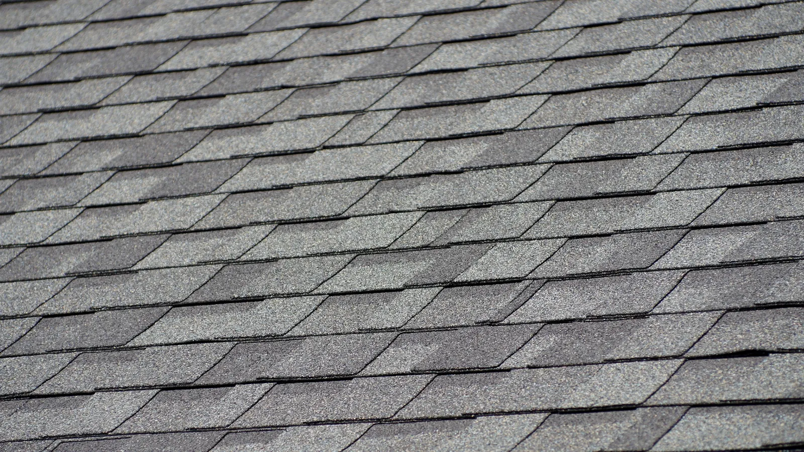 Overlapping rows of gray architectural asphalt shingles viewed from above