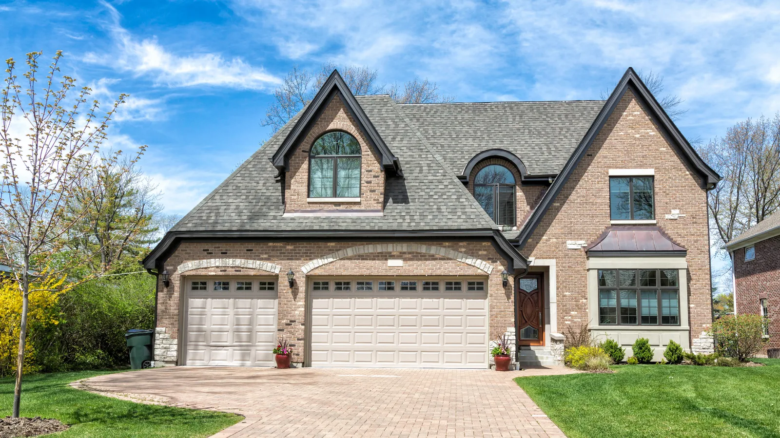 Steep gabled brick two-story beneath a gray architectural shingle roof