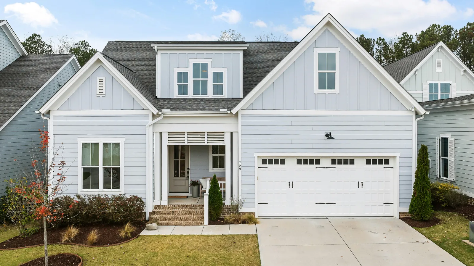 Light blue siding home with a white garage door and gray shingle roof