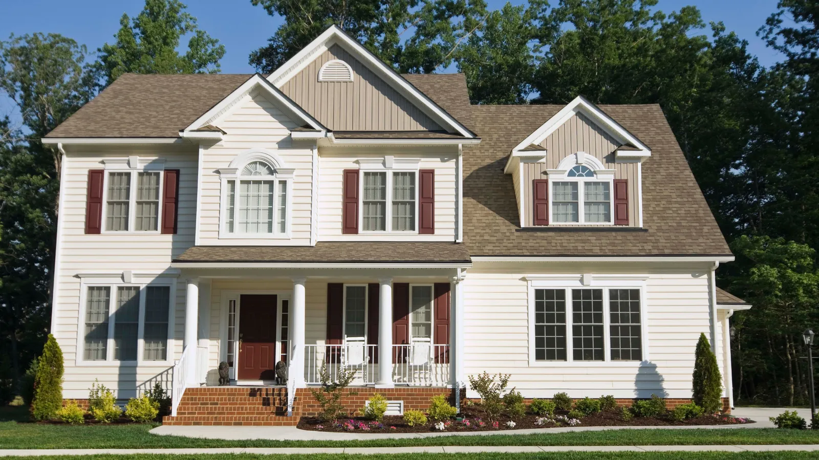 Brown shingle roof and covered porch on a cream two-story house