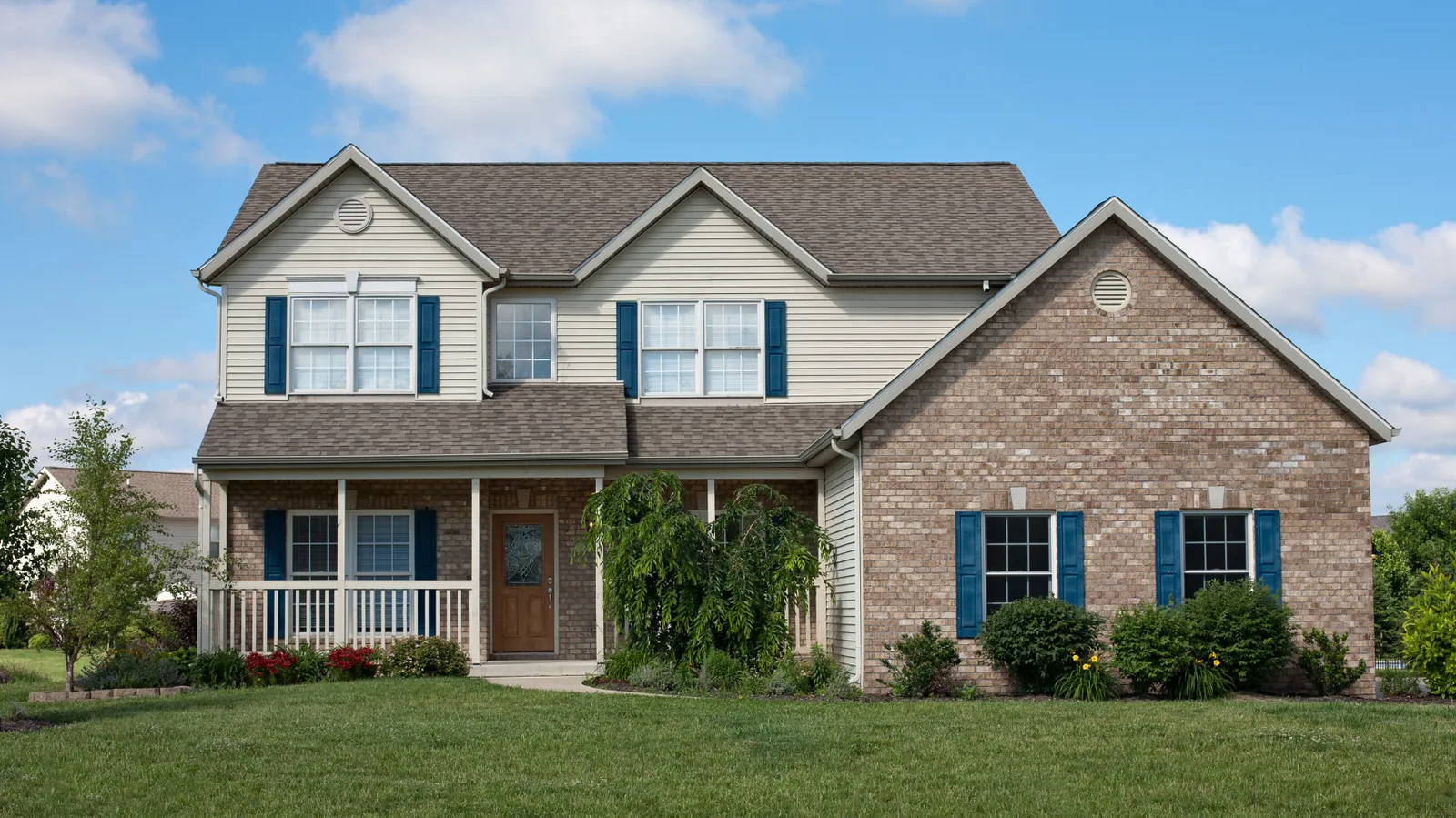 Brick and siding two-story home with brown shingle roof