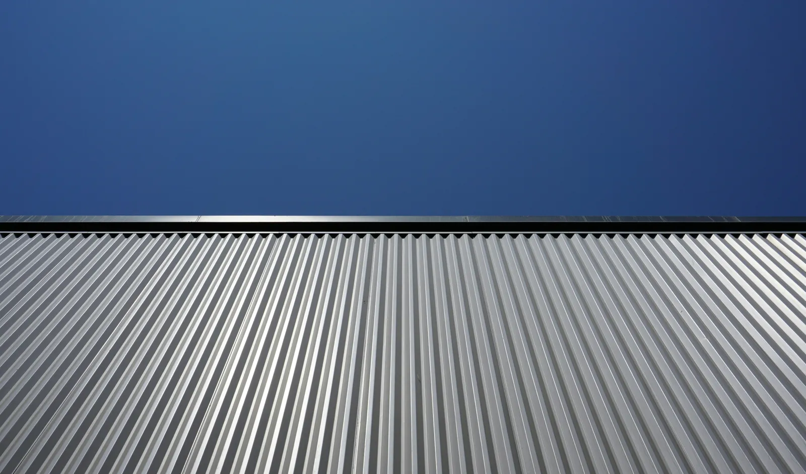 Silver corrugated metal panels against a deep blue sky