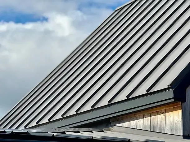 Wood soffit beneath a standing seam metal roof slope